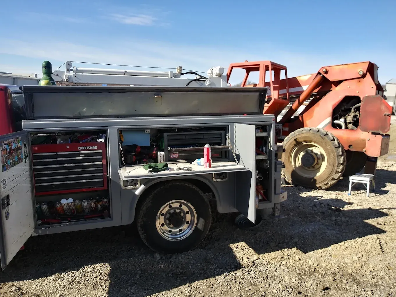 Fire truck with tool compartments beside a red construction tractor